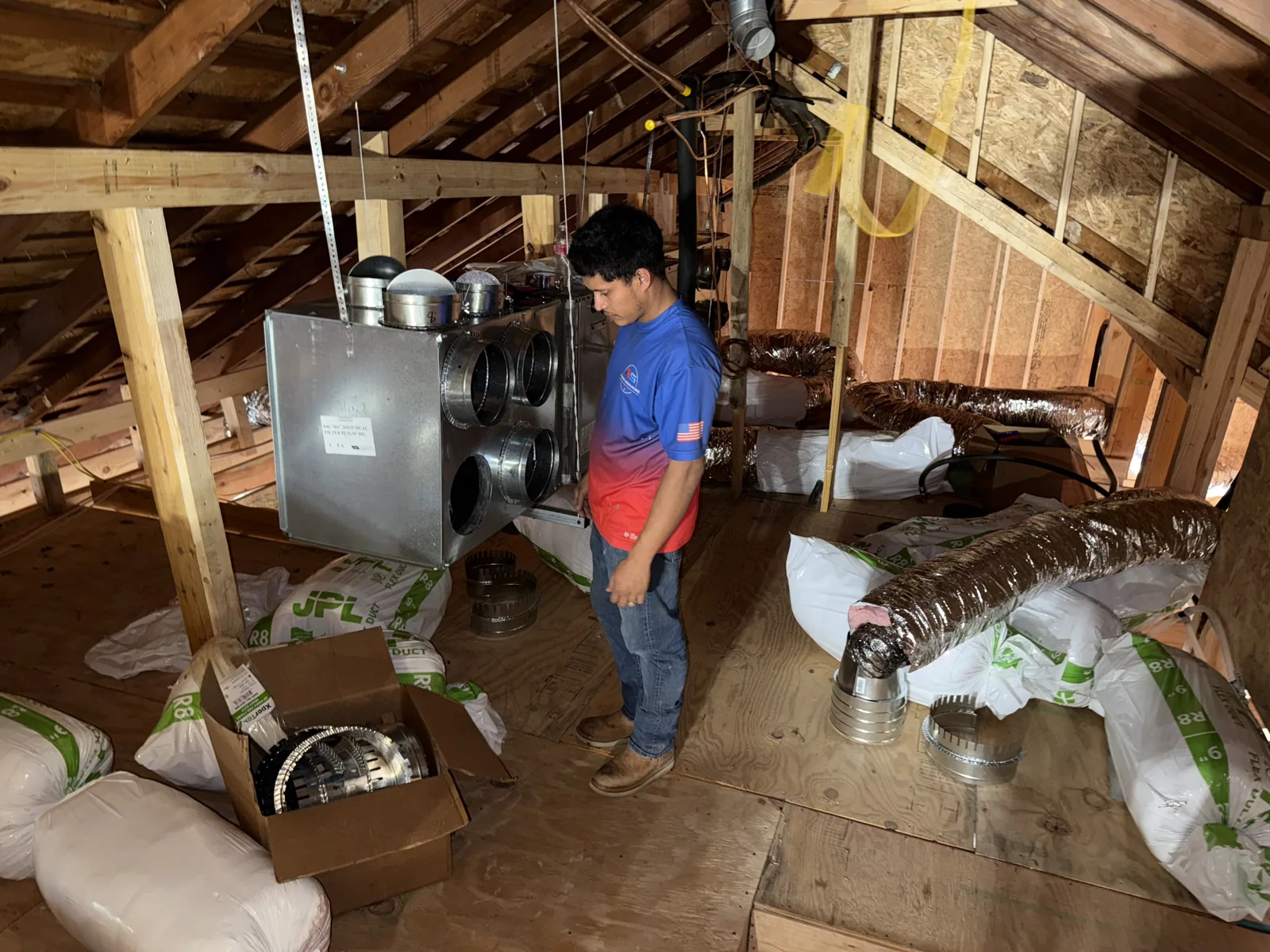 Roma technician working beside HVAC equipment in an attic